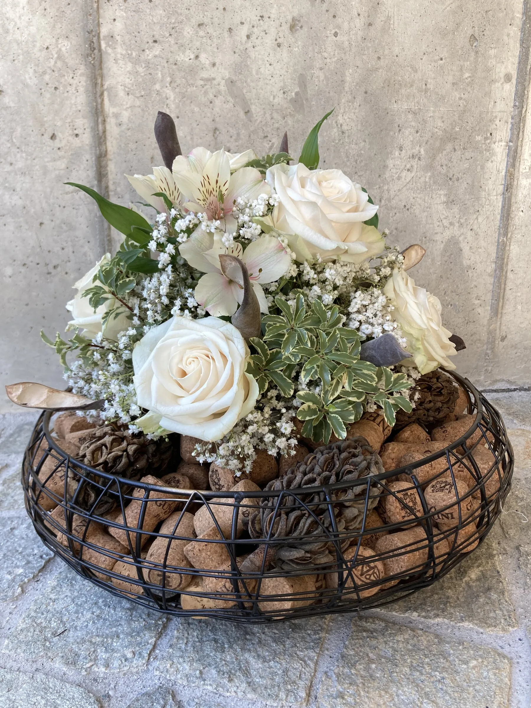 Gesteck im Drahtkorb mit weissen Rosen, Schleierkraut und Korken