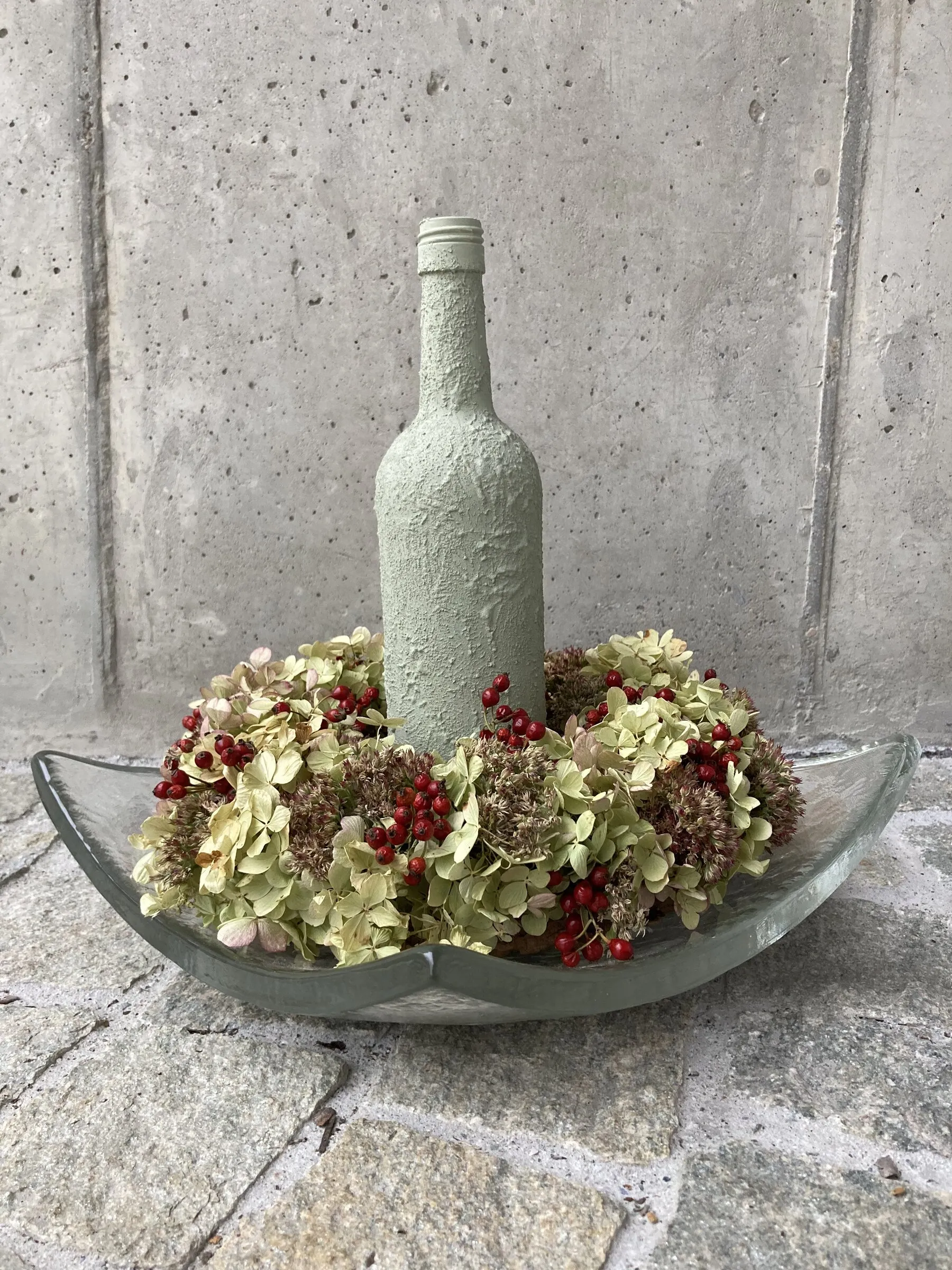 Dekorierte Flasche mit Kranz aus getrockneten Hortensien und roten Beeren
