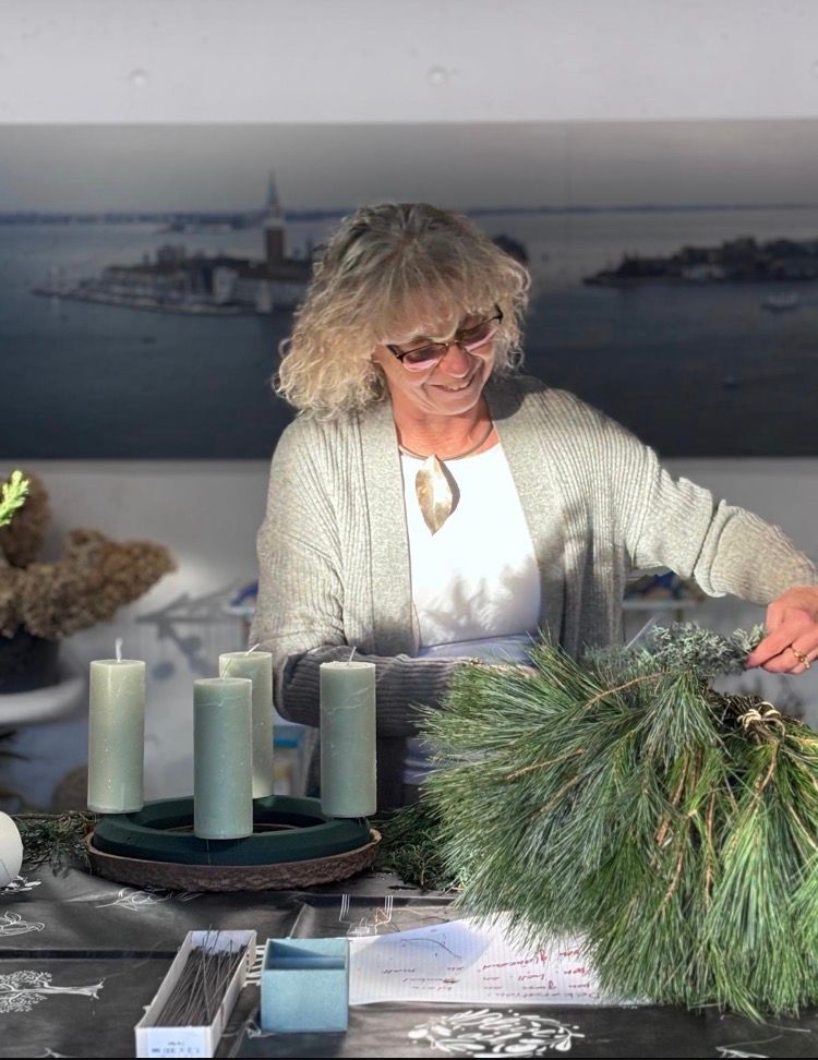 Kursleiterin bindet einen Adventskranz im Floristikkurs