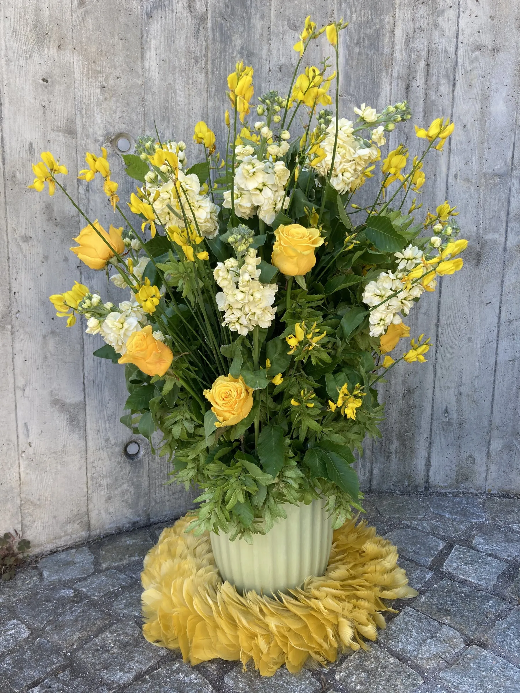 Gelbes Gesteck mit Levkojen und Rosen auf einer Manschette aus Chrysanthemenblüten