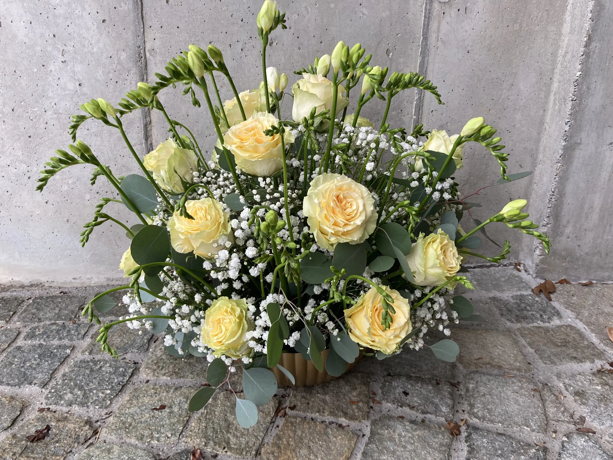 Gesteck mit cremefarbenen Rosen, Lisianthus, Schleierkraut und Eukalyptus