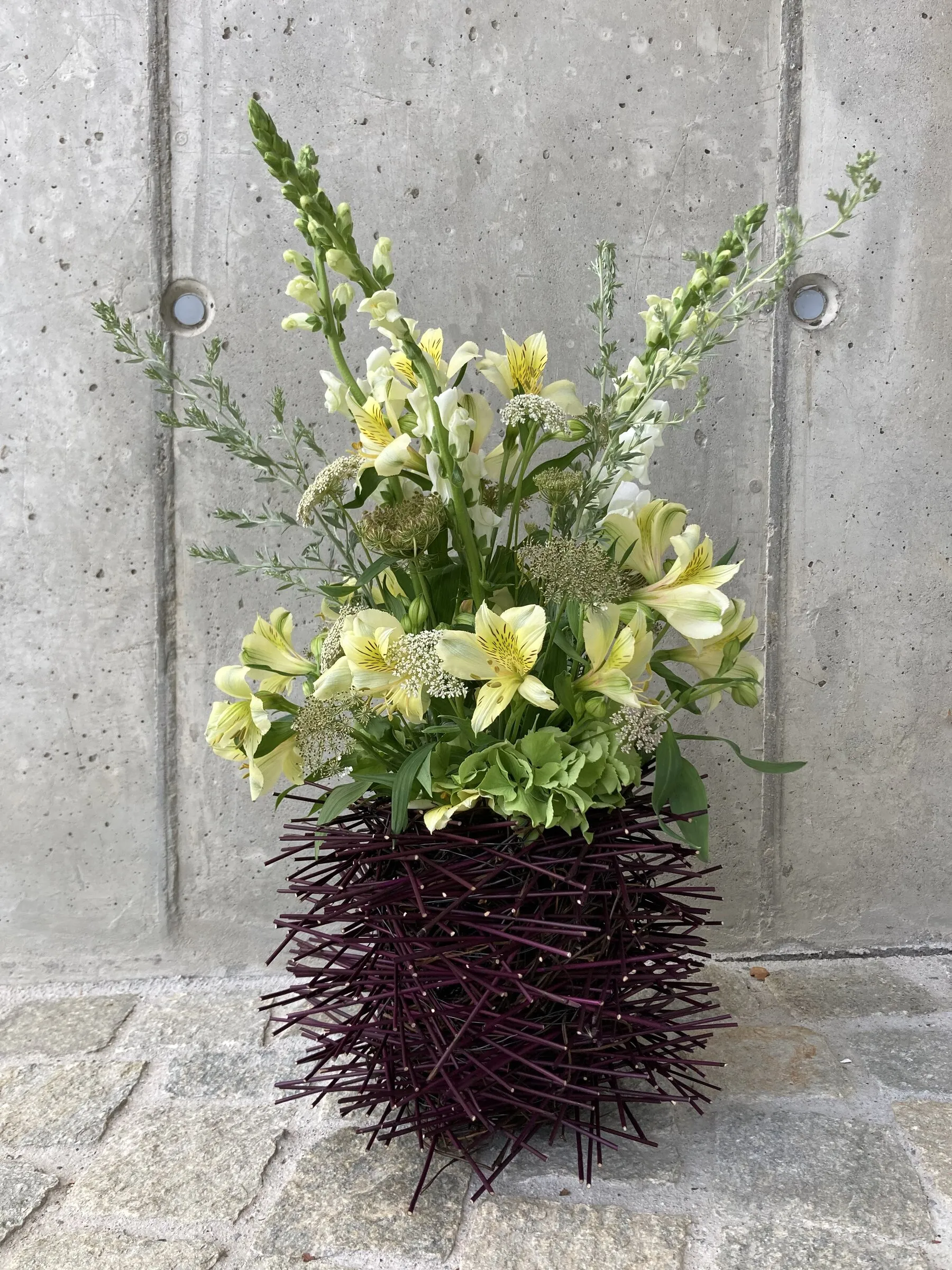 Hohes Gesteck in Cremetönen mit Alstroemerien und Löwenmäulchen auf dunkler Dornenvase