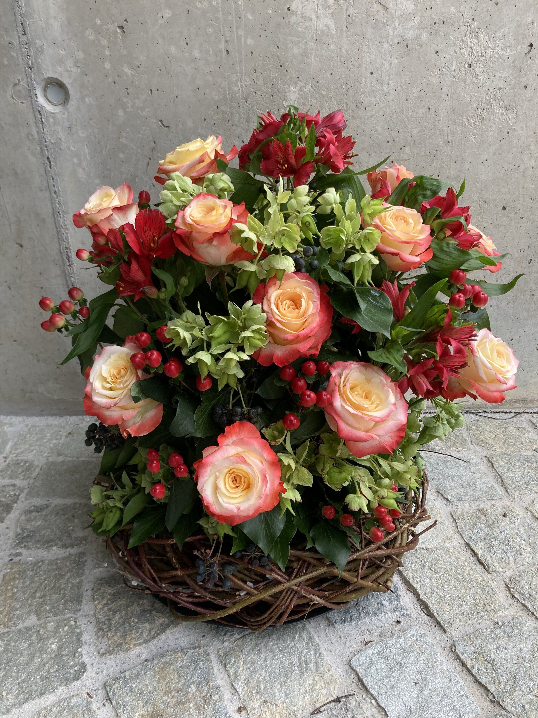 Korbgesteck mit apricotfarbenen Rosen, roten Alstroemerien und Beeren