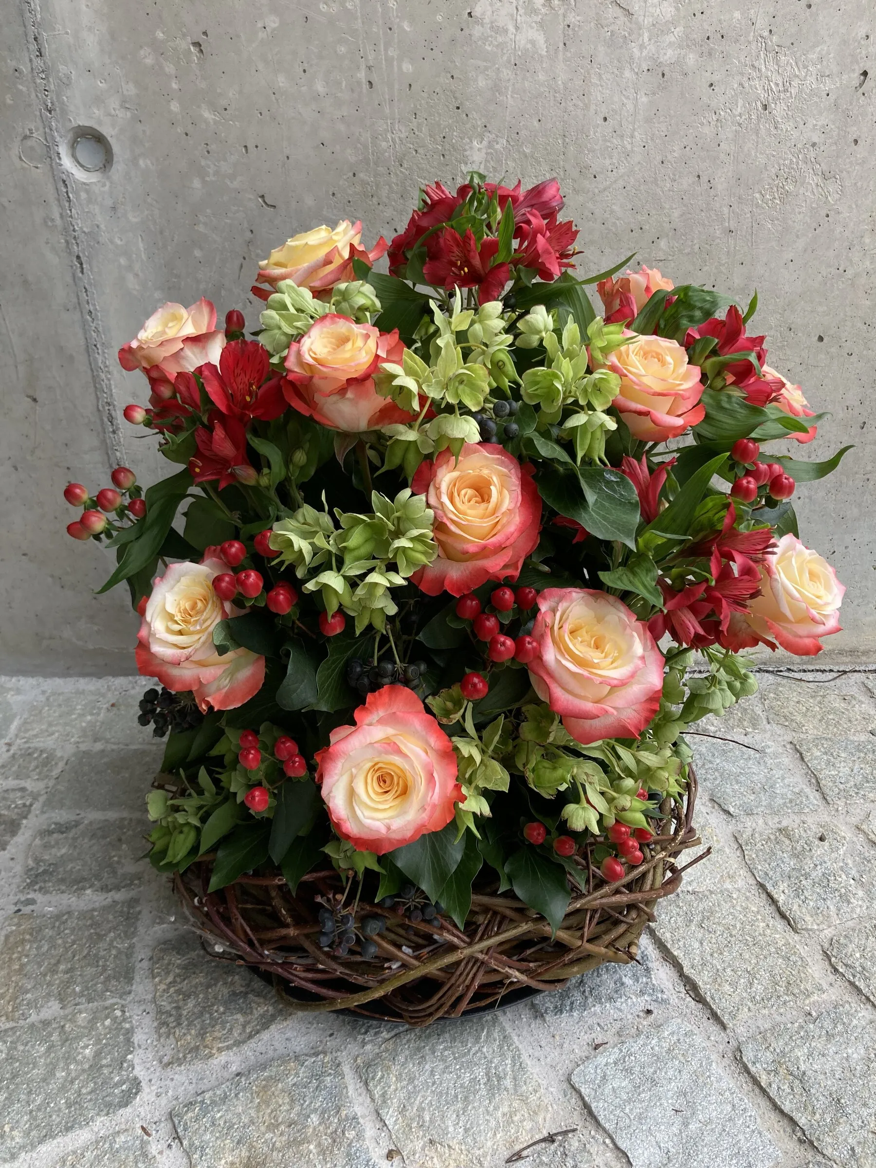 Korbgesteck mit apricotfarbenen Rosen, roten Alstroemerien und Beeren