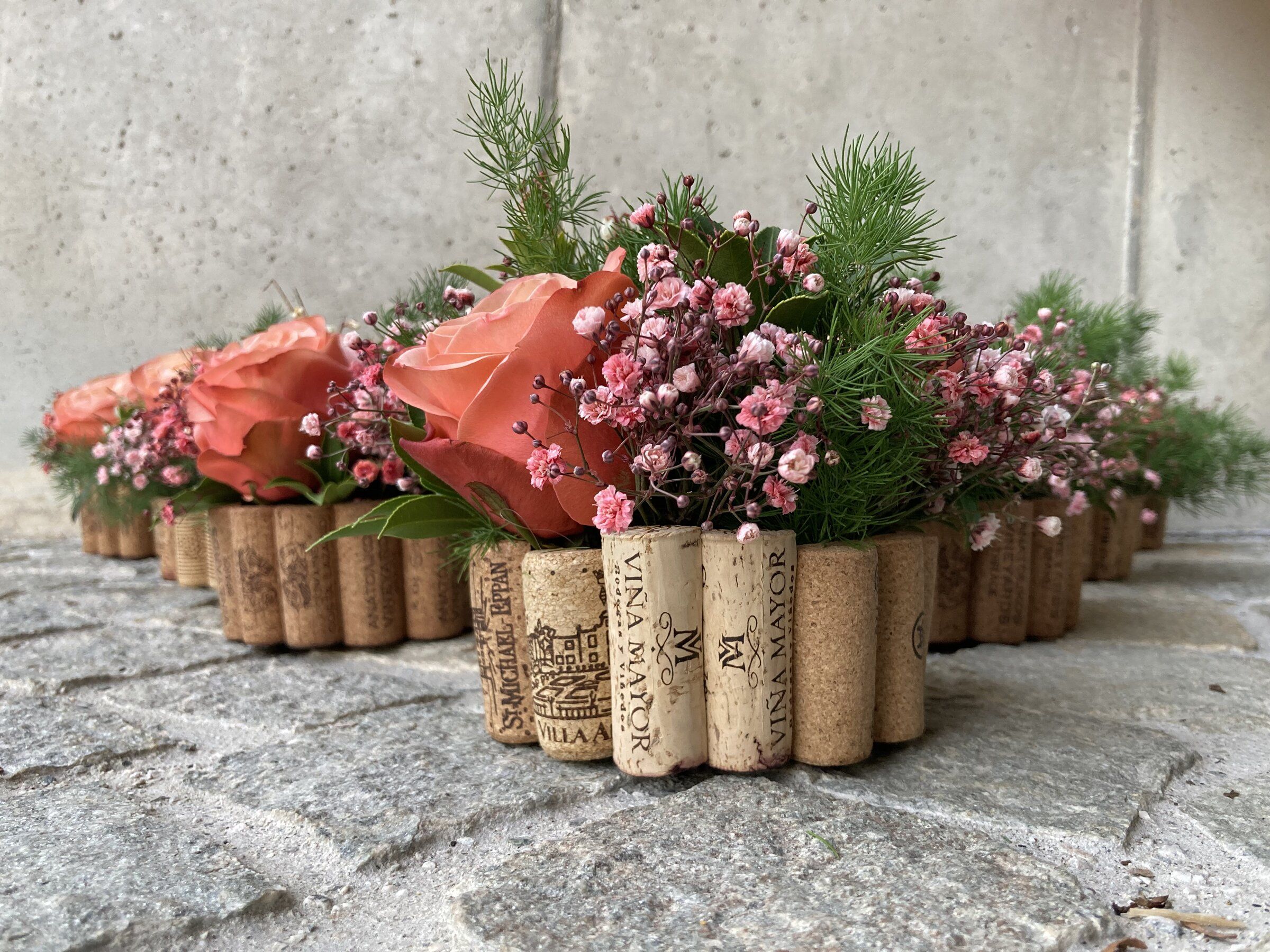 Gefässe mit Korkmantel, gefüllt mit apricotfarbenen Rosen und Schleierkraut