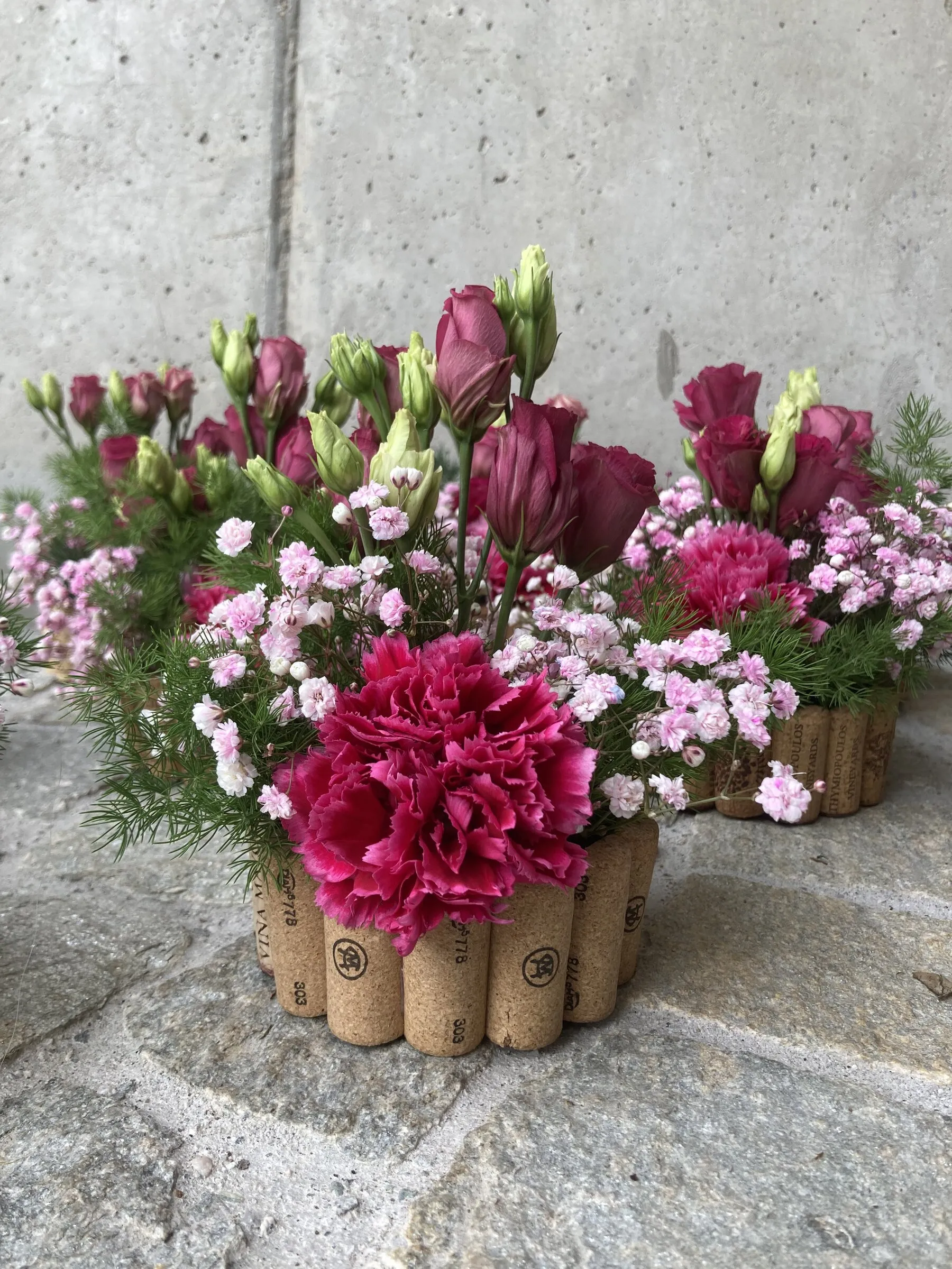 Gefässe mit Korkmantel, gefüllt mit pinken Nelken und Lisianthus