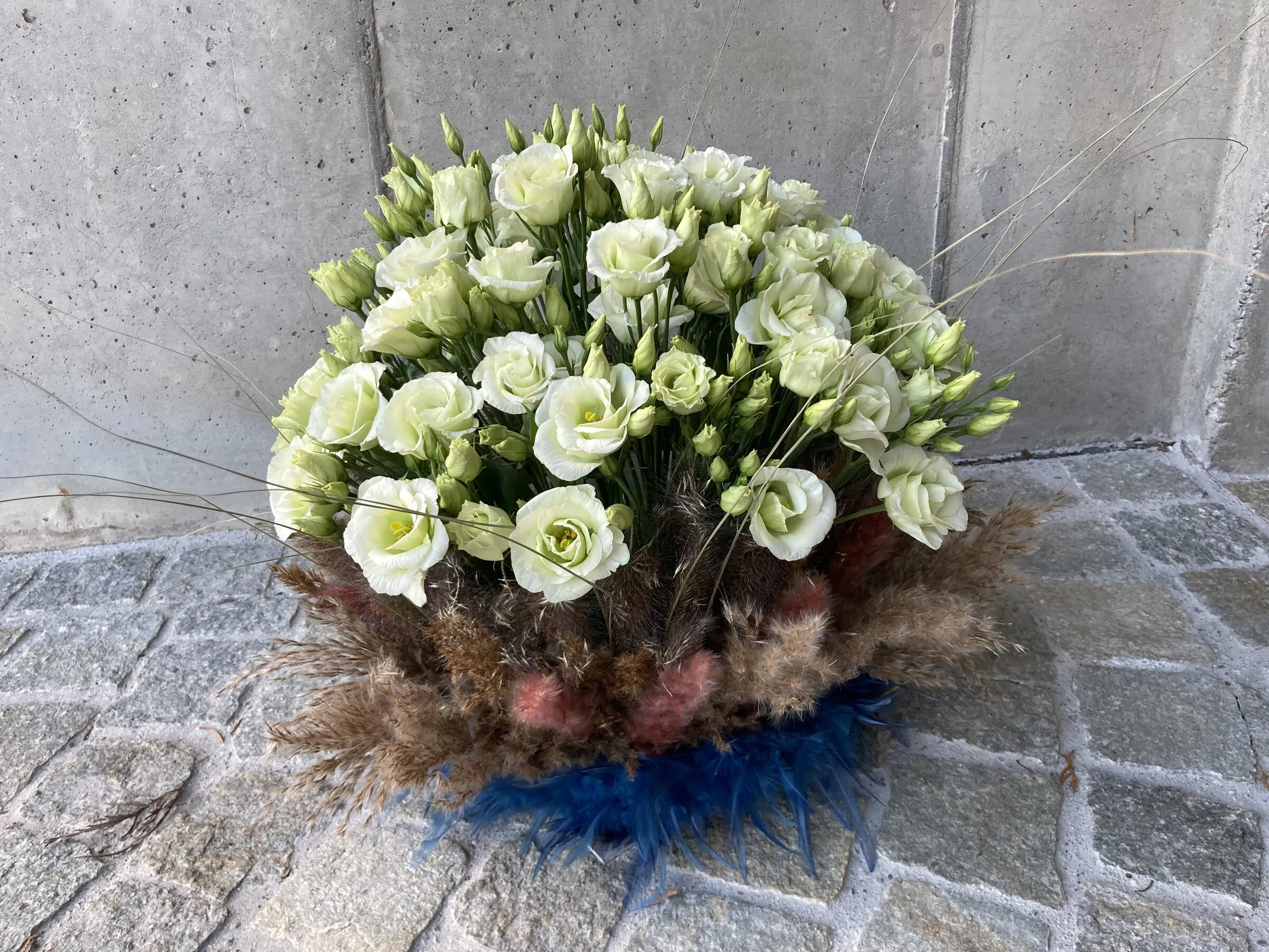 Dichte Kuppel aus weissem Lisianthus auf Pampasgras mit blauen Federn