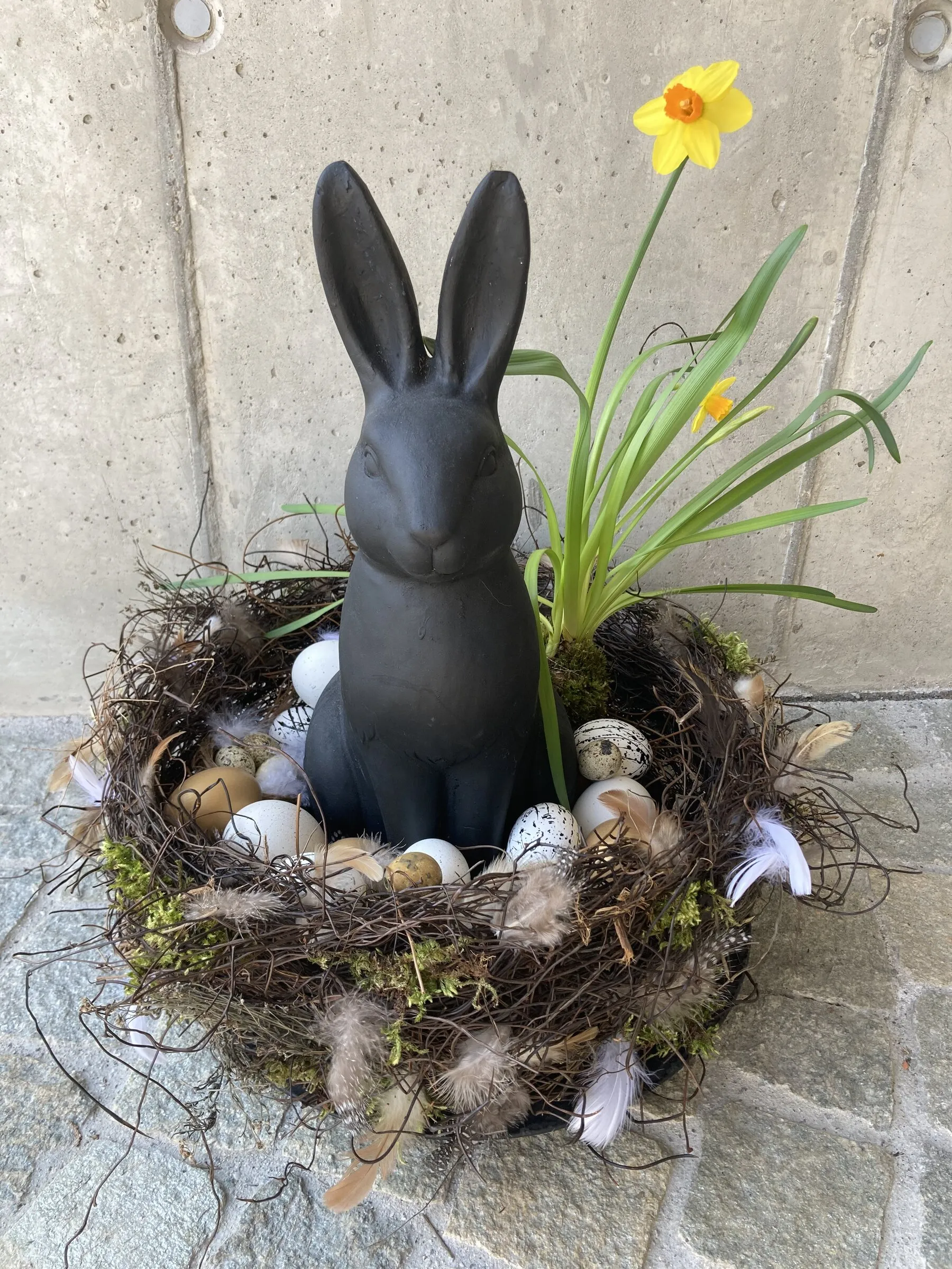 Osterdekoration mit Hasenfigur, Nest, Wachteleiern und Narzissen
