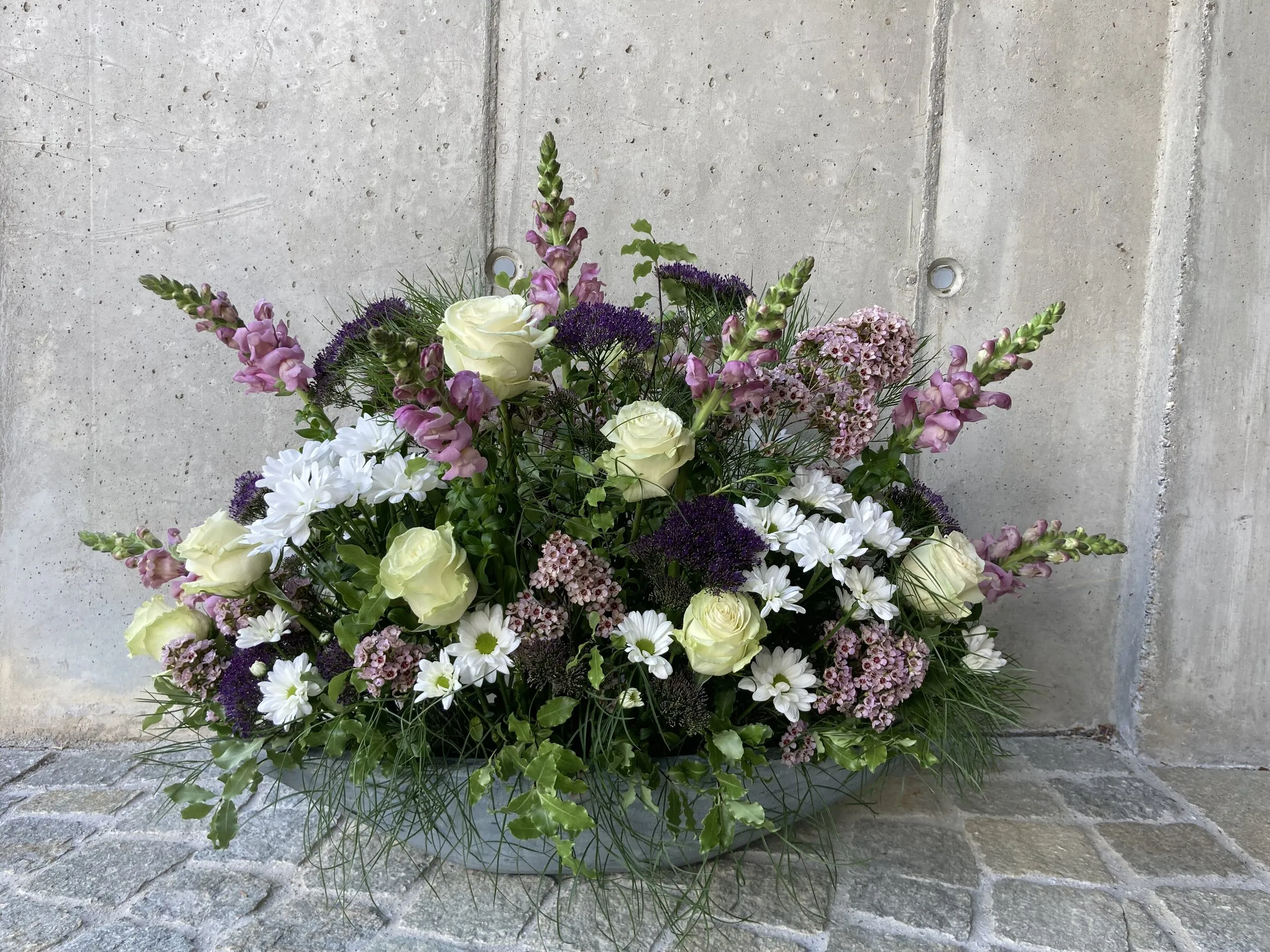 Ovales Gesteck in Weiss und Violett mit Löwenmäulchen und Astern