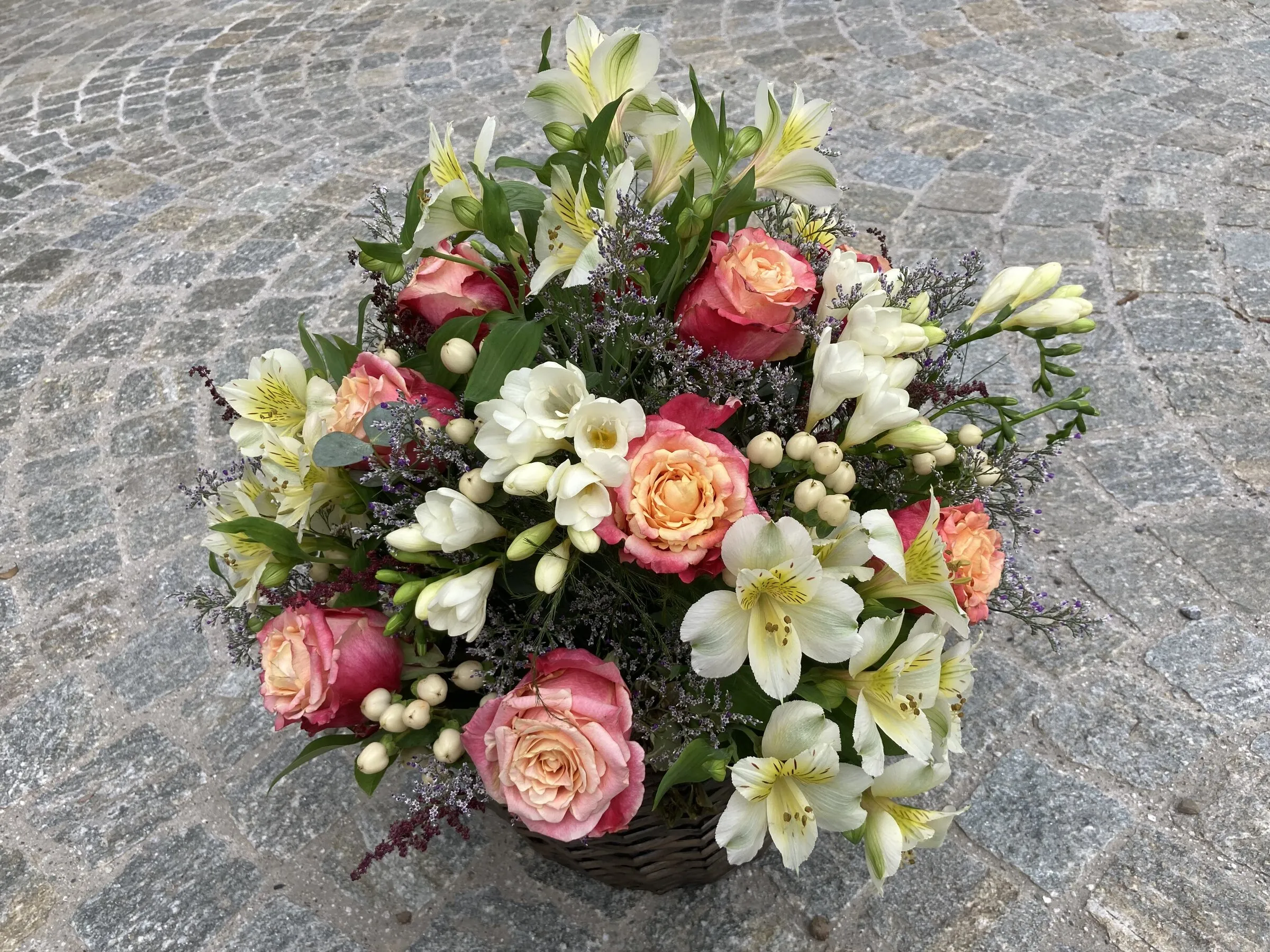 Rundes Gesteck mit korallenfarbenen Rosen, weissen Freesien und Alstroemerien