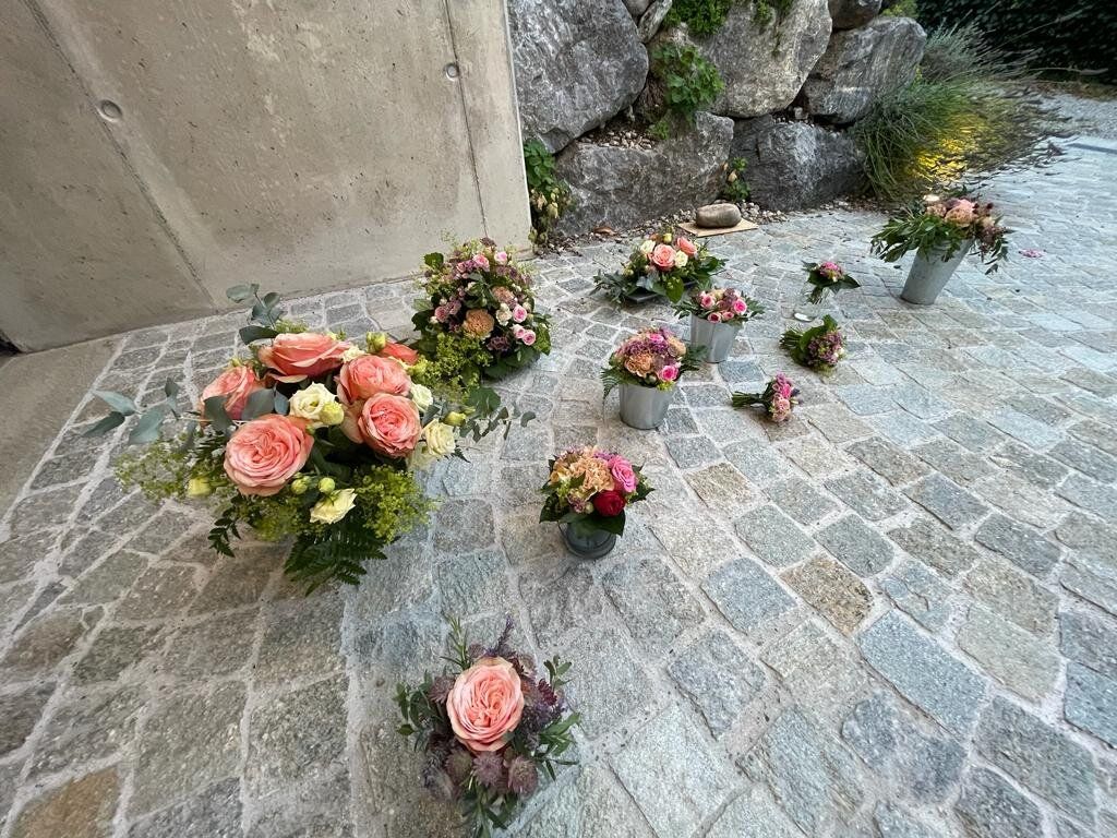 Serie kleiner Tischgestecke und Ansteckblumen mit apricotfarbenen Rosen