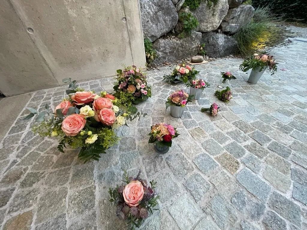 Serie kleiner Tischgestecke und Ansteckblumen mit apricotfarbenen Rosen
