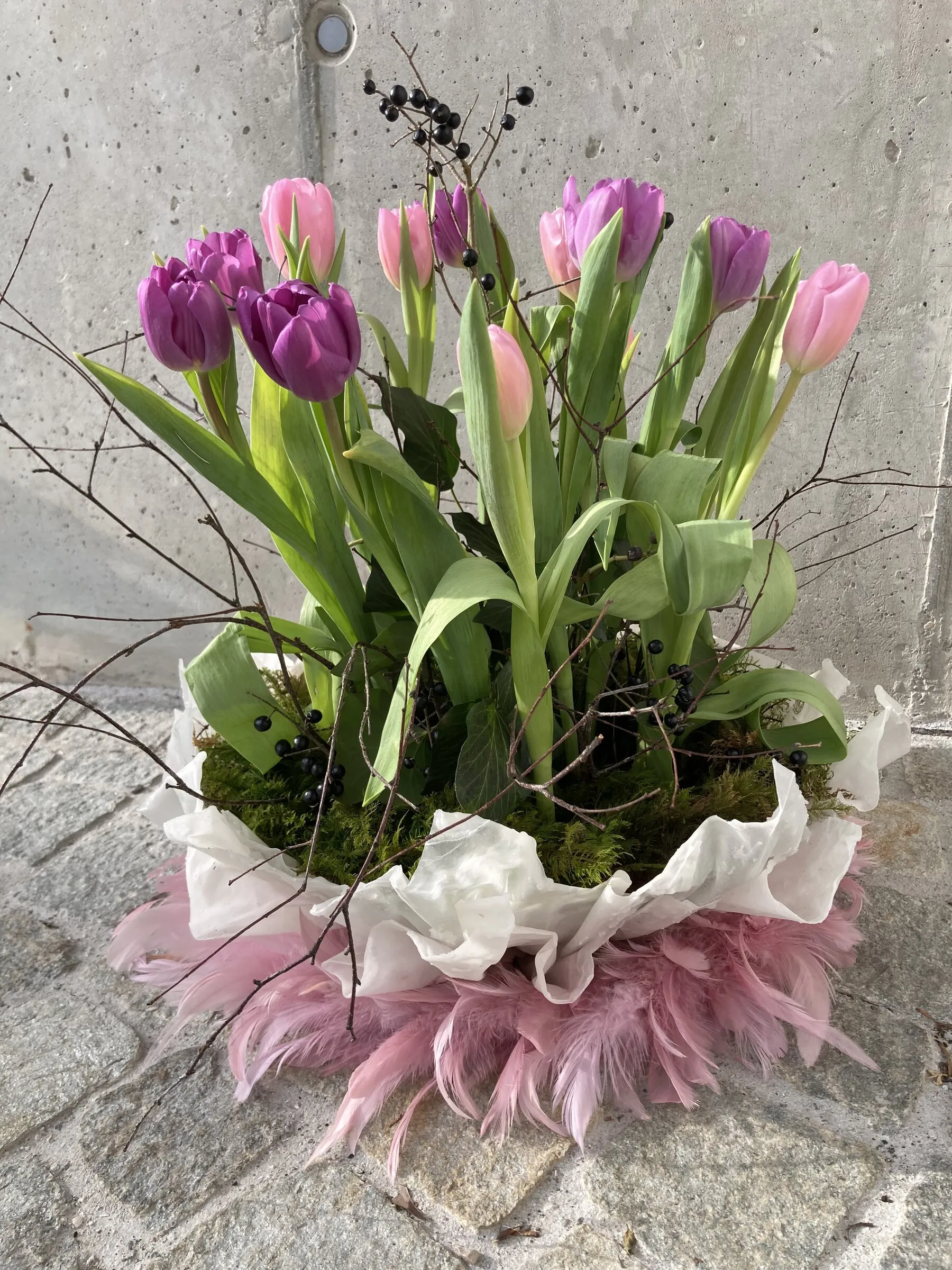 Tulpengesteck in Lila und Rosa auf Moos mit rosa Federmanschette