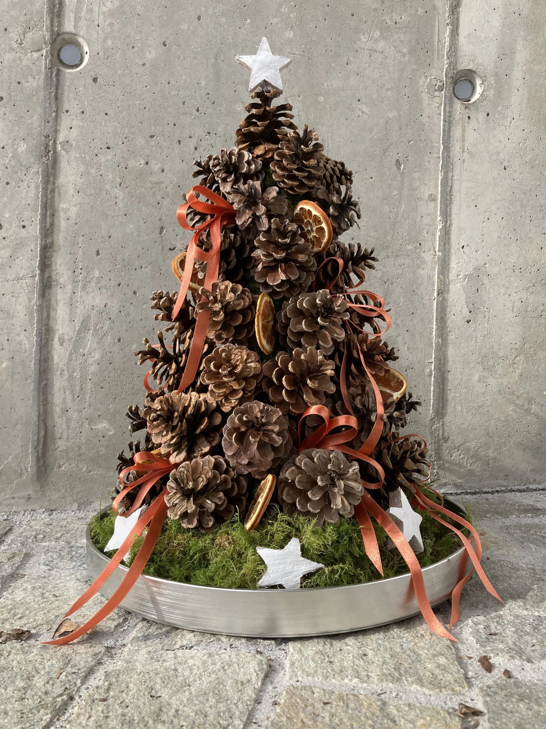 Weihnachtsbaum aus Tannenzapfen mit Orangenscheiben und Bändern