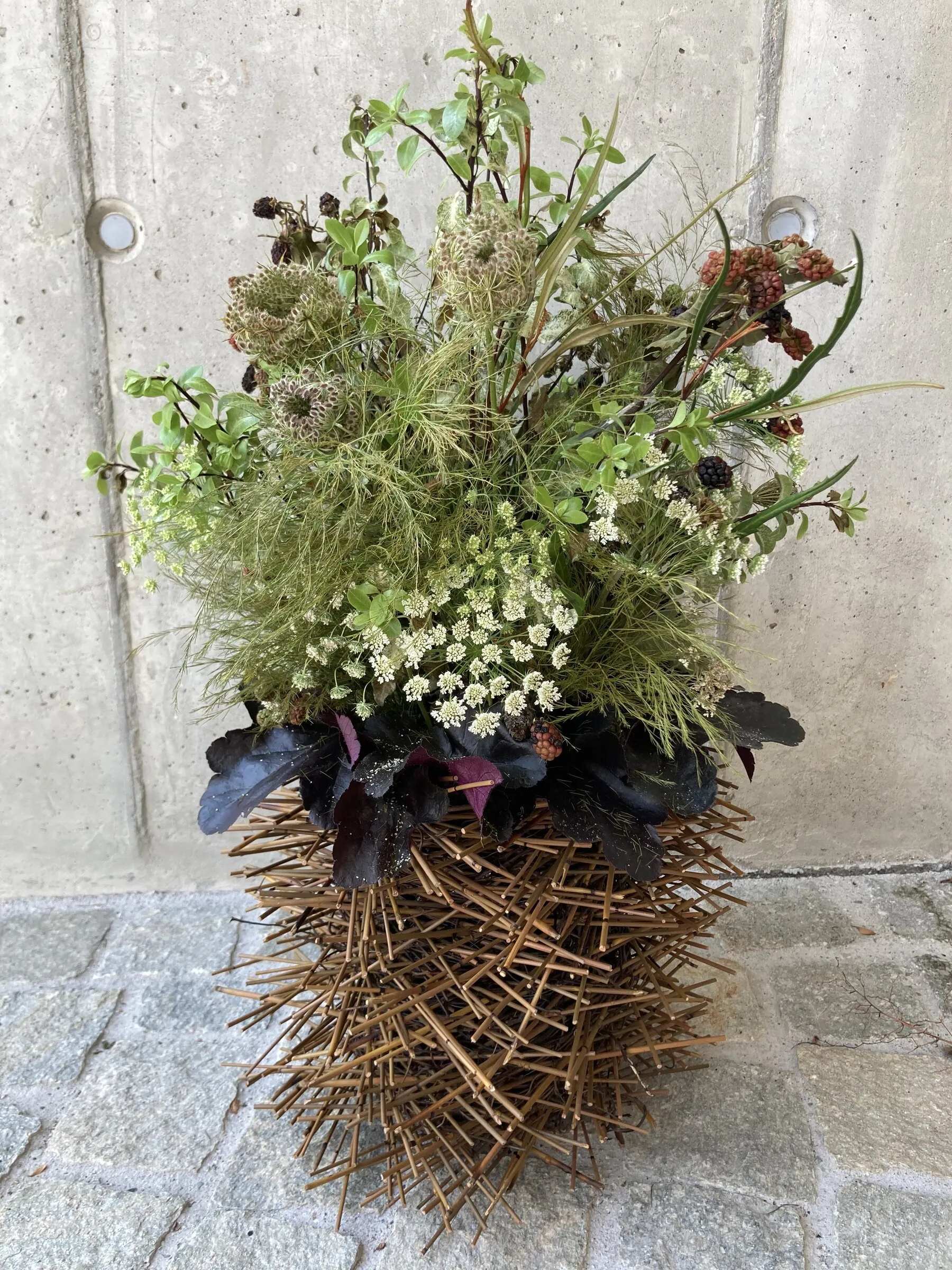 Wild wirkendes Gesteck mit Ammi und Wiesenblumen auf goldener Dornenvase